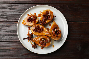 Wall Mural - Delicious pears with caramel sauce, pecan nuts and anise stars on wooden table, top view