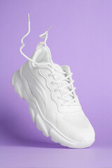 Wall Mural - Stylish white sneaker in air against violet background