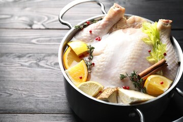 Wall Mural - Whole raw turkey, citrus fruits and spices in pot on black wooden table, closeup. Space for text