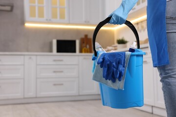 Wall Mural - Woman with bucket with cleaning supplies in kitchen, closeup