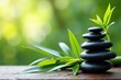 A Tranquil Arrangement of Smooth Black Stones and Fresh Green Bamboo Leaves Set Against a Soft Focus Natural Background for Serenity and Relaxation
