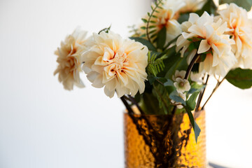 Wall Mural - Close up beautiful beige artificial flowers in a vase on window sill