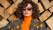 © PaulShlykov - Fashionable woman poses with stylish sunglasses against a backdrop of wooden logs in a trendy outfit