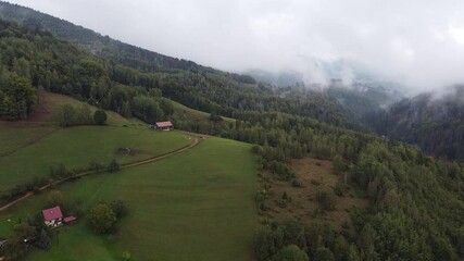 Poster - Drone footage of a forested mountain behind clouds and a view of an old house buildding