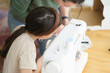 © PeterPike - A little cute girl wearing glasses sitting at a sewing machine at a wooden table in a room. Educational and creative children's concept.