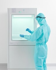 Leinwandbilder - Minimalist Clinical Setup Technician in Teal PPE Handling Samples in Sterile Lab Environment - Precision Medical Research and Workflow Efficiency for Health Innovations