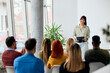 © bnenin - Woman Giving a Presentation to an Engaged Group in a Modern Setting