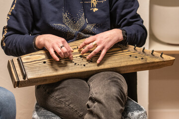 Wall Mural - Fingers of a girl playing kankles, Lithuanian plucked string instrument belonging to the Baltic box zither family known as the Baltic psaltery, in Latvian kokles, Estonian kannel, Finnish kantele