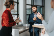© qunica.com - A group of business employees in a modern office kitchen area, engaged in a strategic discussion. Natural light highlights their focused and collaborative atmosphere, emphasizing teamwork and