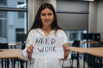 Wall Mural - Young woman in office holding banner with text of need work