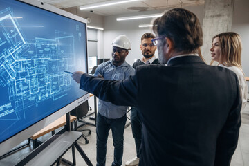 Wall Mural - Construction plan on the screen. Group of office workers are indoors together