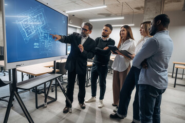 Wall Mural - Building plan on screen. Group of office workers are indoors together