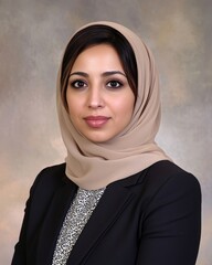 Wall Mural - A young woman wearing a hijab and business attire, smiling confidently against a neutral background.