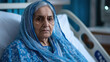 © vstudio - Elderly Indian woman with blue headscarf in hospital bed somber and thoughtful with wrinkled face