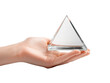 © tinnakorn - A hand holds a clear triangular prism, showcasing its geometric shape and clarity.