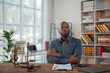 © Tj - Serious African American lawyer sitting with crossed arms at a desk, surrounded by justice scales, gavel, and contract, exuding confidence and professionalism in a modern office