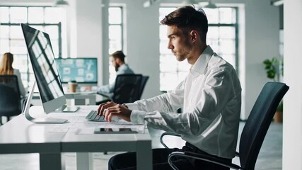 Aufkleber - Young professional engineer focusing intently, typing precisely on keyboard while working on computer project in bright, modern office space with natural light streaming through window