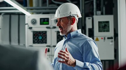 Poster - Professional industrial engineer wearing protective hardhat explaining complex work process to colleagues inside technical server room with advanced digital infrastructure in dramatic slow motion