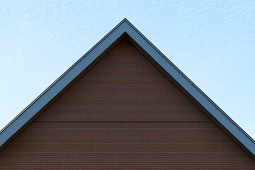 Poster - Peaked roof under a clear sky. The gable wall displays reddish brown brickwork complemented by dark trim, creating clean lines against the light backdrop.