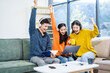 © Phushutter - Three Asian young adult students sit in university living room, discussing their study abroad experiences, academic research, preparing thesis report, planning future global education opportunities.