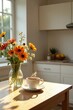 © Kittipat - Warm sunlight illuminates a kitchen table with a steaming cup of coffee and a vase of vibrant orange and yellow flowers.