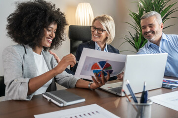 Wall Mural - Three busy happy middle aged professional business man and two women executive leaders team using laptop working on computer at work desk having conversation on financial project at meeting in office.