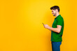 © deagreez - Profile side view portrait of his he nice attractive cheerful cheery addicted guy using digital device smm like isolated over bright vivid shine vibrant yellow color background