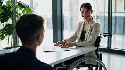 Aufkleber - Confident businesswoman using a wheelchair discussing with a male colleague during a productive meeting in a modern office, captured in slow motion