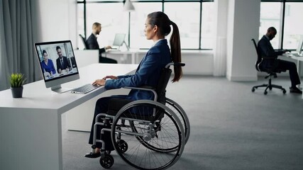 Aufkleber - Businesswoman in a wheelchair uses a desktop computer to participate in a video conference with colleagues in a modern office, captured in slow motion