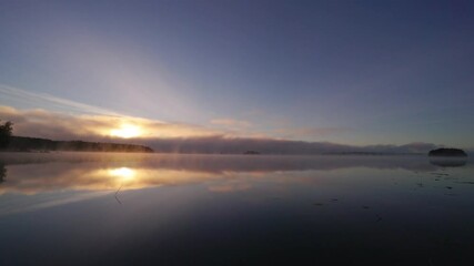 Wall Mural - Scenic morning view of clouds on a lake with reflection of sun at sunrise