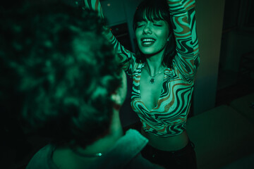 Poster - A young woman enjoying a vibrant dance moment at a house party. The lively atmosphere is enhanced by colorful lighting and music.