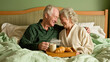© mikhailberkut - Elderly caucasian couple enjoying breakfast in bed with coffee and croissants