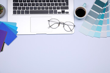Poster - Designer's workplace with color palettes, cup of coffee, glasses and laptop on grey table, flat lay. Space for text