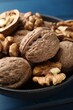 © New Africa - Fresh walnuts in bowl on blue table, closeup
