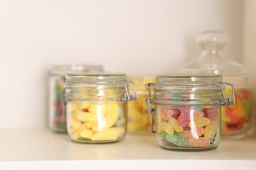 Wall Mural - Tasty gummy candies in jars on shelf, closeup