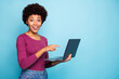 © deagreez - Photo of cute stylish trendy black model pointing at laptop recommending you to purchase it requesting to follow on social media wearing hreen sweater jeans denim isolated vivid color blue background