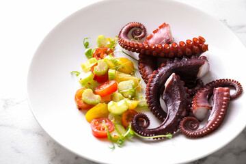 Wall Mural - Plate with tasty boiled octopus tentacles and salad on white marble table, closeup