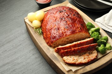 Wall Mural - Delicious turkey meatloaf with vegetables served on black table, closeup