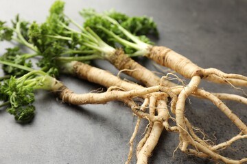 Wall Mural - Parsley roots with leaves on black table, closeup