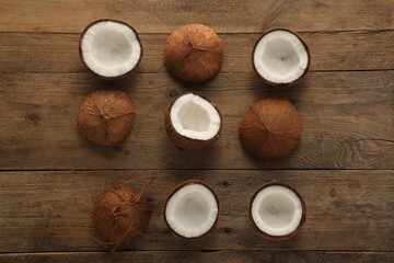 Wall Mural - Halves of fresh coconuts on wooden table, flat lay