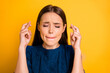 © deagreez - Close up photo of cute nice girlfriend with her fingers crossed expecting something waiting for result while isolated with yellow background