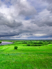 Wall Mural - cloudy sky with a green field in the background