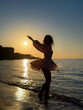 © Sunny studio - Silhouette of young woman dancing at the sandy beach