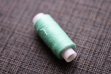Poster - A single spool of thread sitting on a table, possibly for sewing or crafting projects.