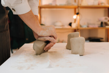 Poster - Craftswoman is preparing clay for making ceramic crockery. Female potter rolls piece of clay before sculpting.