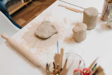 Poster - Hands of a female potter making ceramic clay product on the table in the pottery workshop. Potter is sculpting wet clay for ceramics products.
