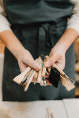 Poster - Wooden craft tools for molding ceramic crockery. Potter holds craft instruments for clay sculpting.