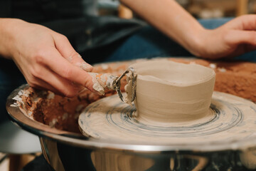 Poster - Artisan forms clay pot with potters tool on the spinning wheel. Creating ceramic earthenware on the manufacturing.