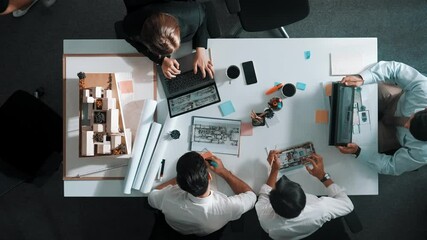 Poster - top view of smart architect engineer writing at blueprint while sitting at meeting table with house 