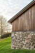 © gamespirit - Wooden house corner with stone base set against a serene landscape, showcasing architectural details and the beauty of nature during early evening